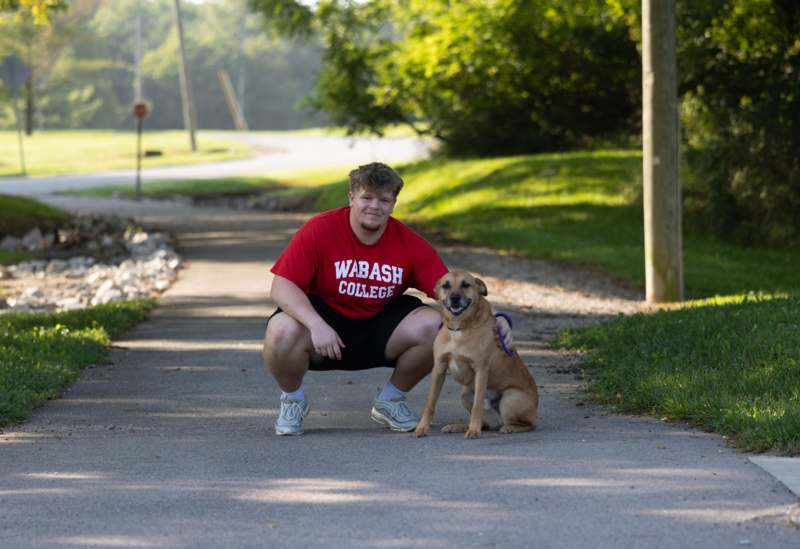 2026 Freshman Community Service - a man squatting next to a dog