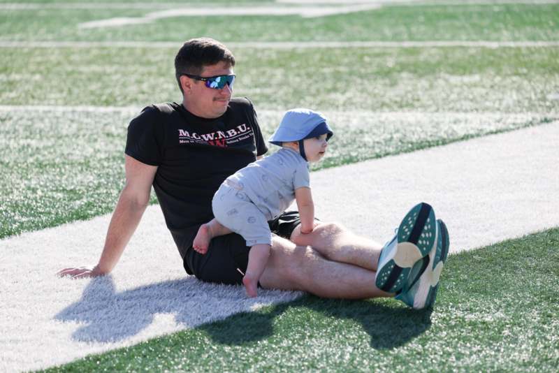 a man sitting on a grass field with a baby