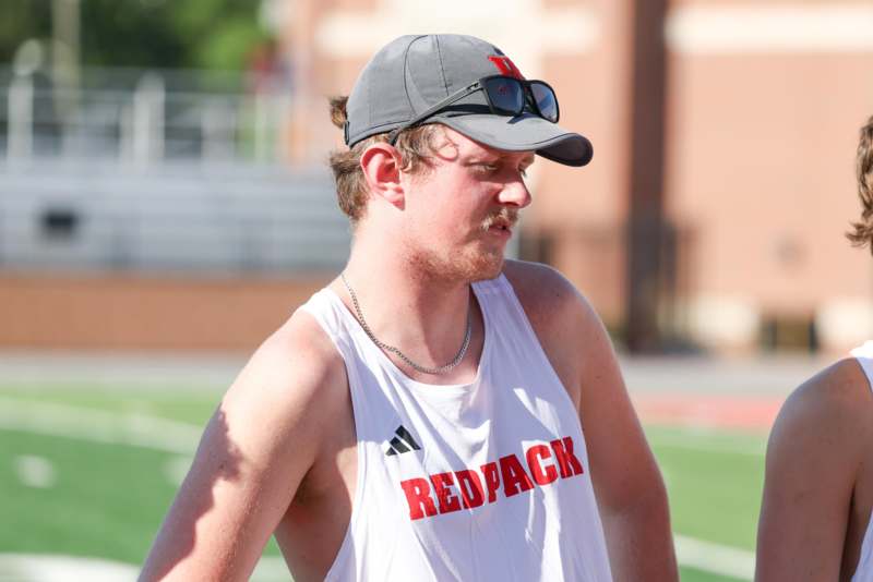 a man in a white tank top and hat
