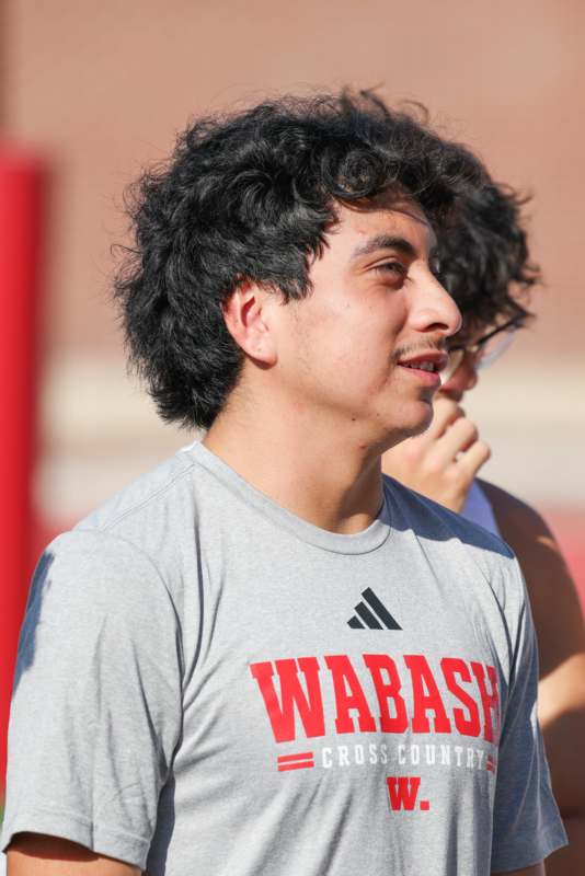 a man with curly hair and a grey shirt with red text