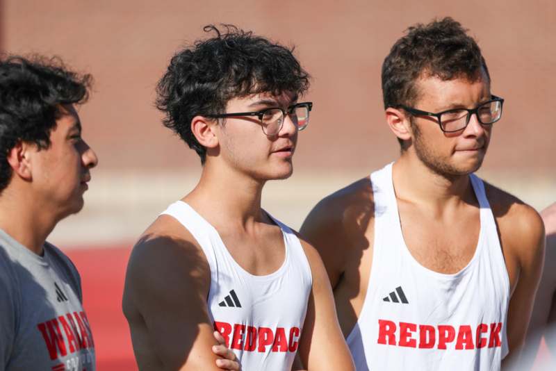 a group of men in white tank tops