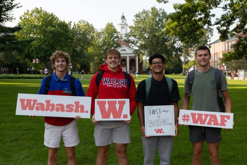 a group of young men holding signs in front of a building