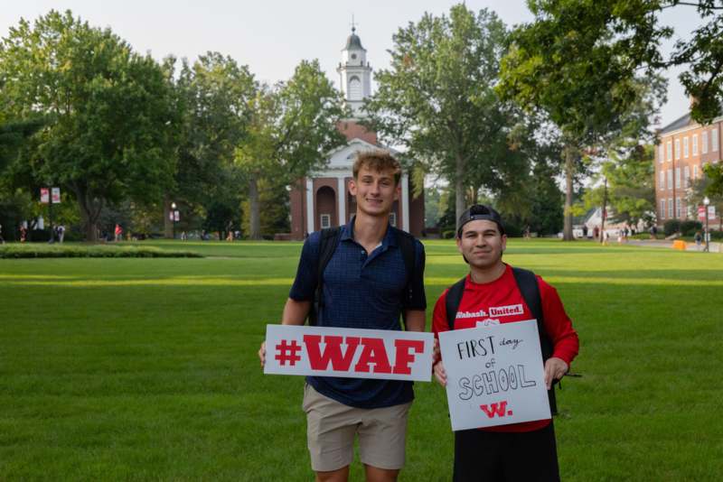 two men holding signs in a park