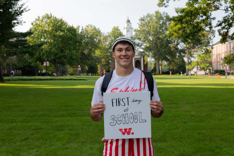 a man holding a sign in front of a school