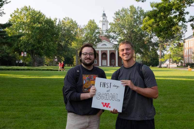 two men holding a sign in front of a building