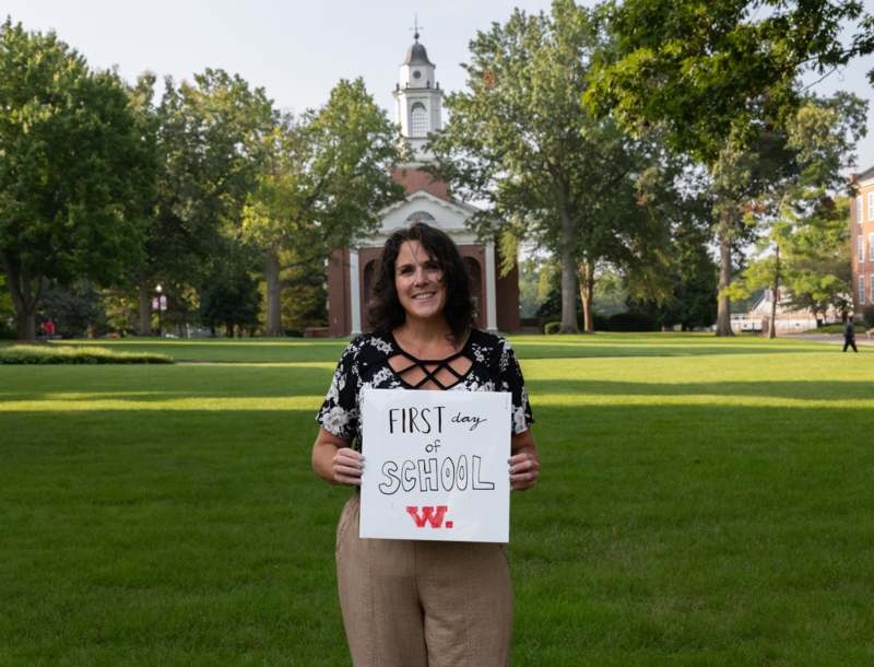 a woman holding a sign in front of a building