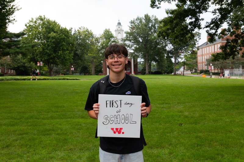 a man holding a sign in front of a school yard