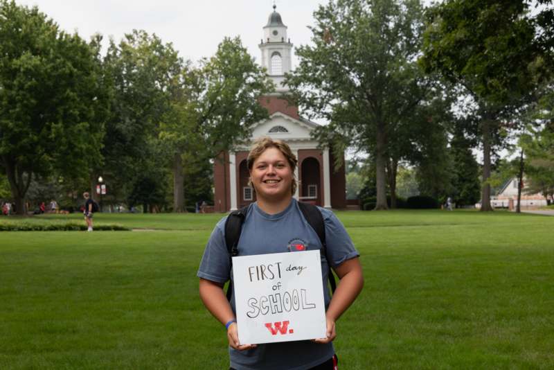 a boy holding a sign in front of a building