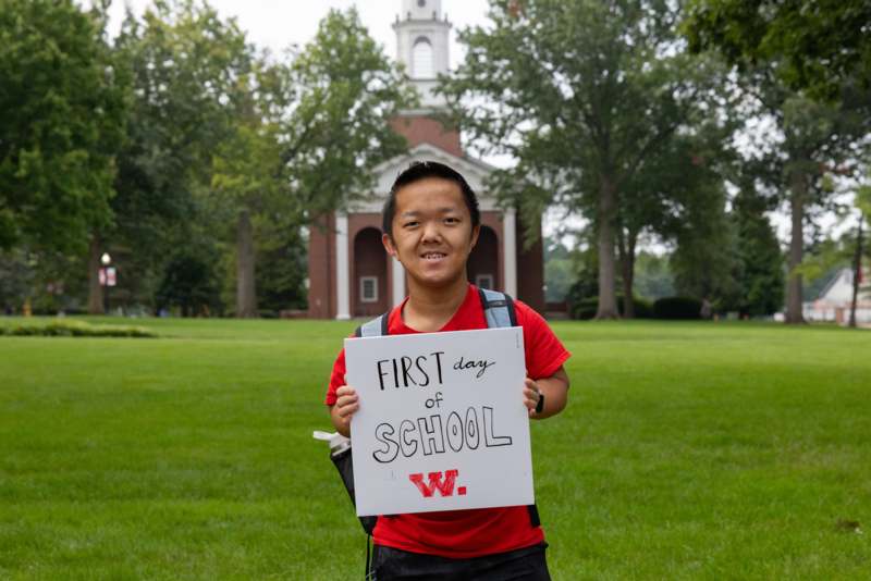 a boy holding a sign in front of a building