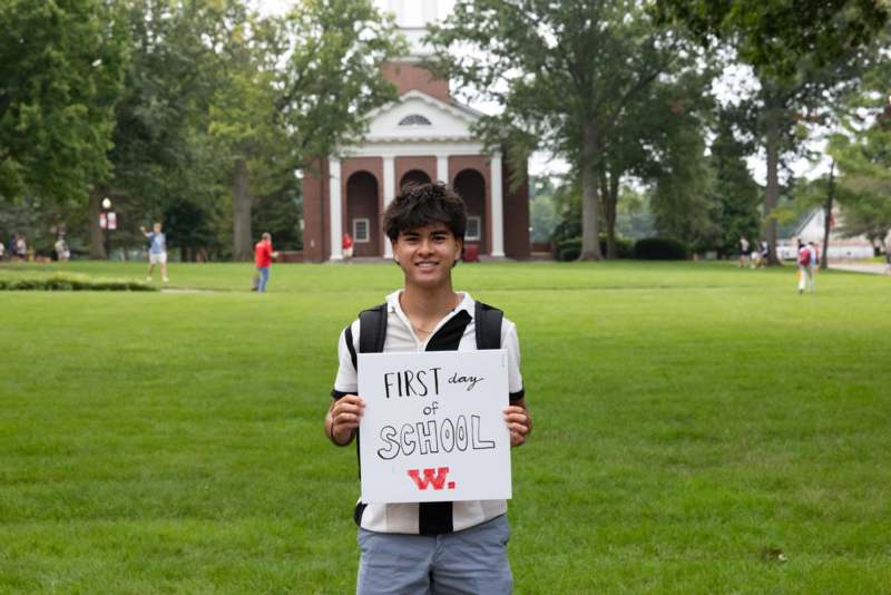 a boy holding a sign in front of a building