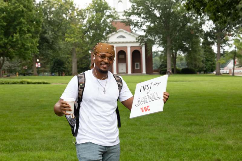 a man holding a sign and a cup of coffee