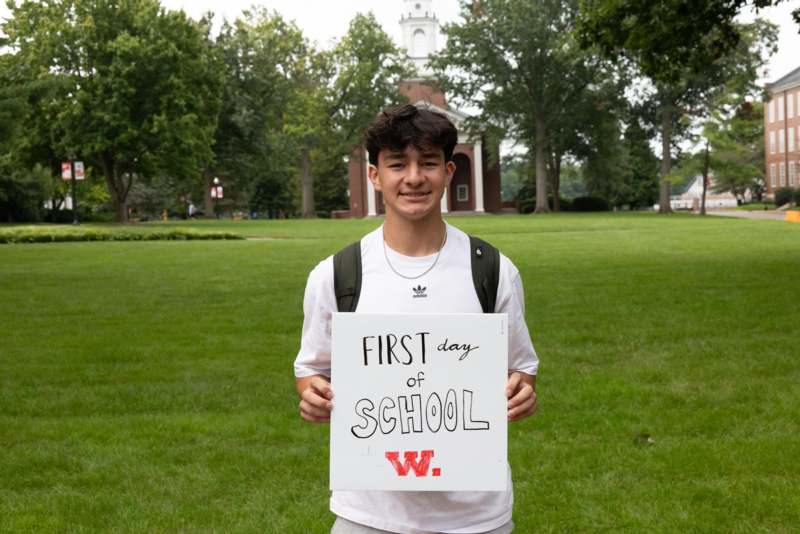 a boy holding a sign in front of a building