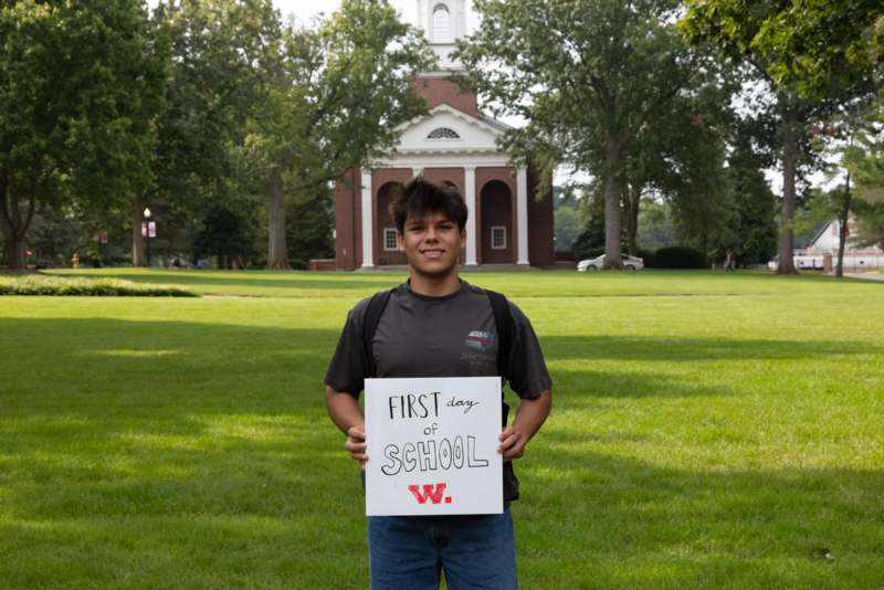 a boy holding a sign in front of a building