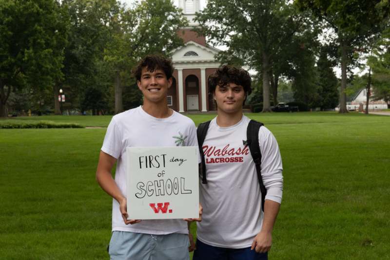 two men standing in front of a building holding a sign