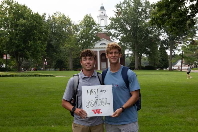 two men holding a sign in front of a building
