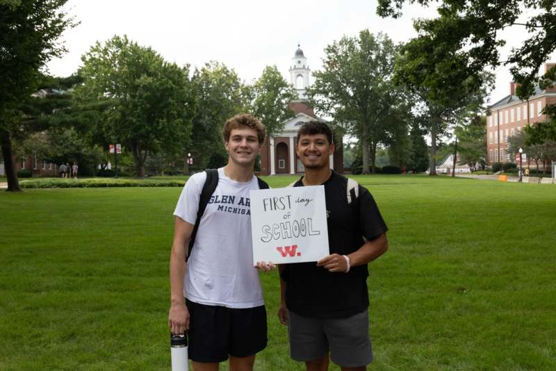 two men standing in a field holding a sign