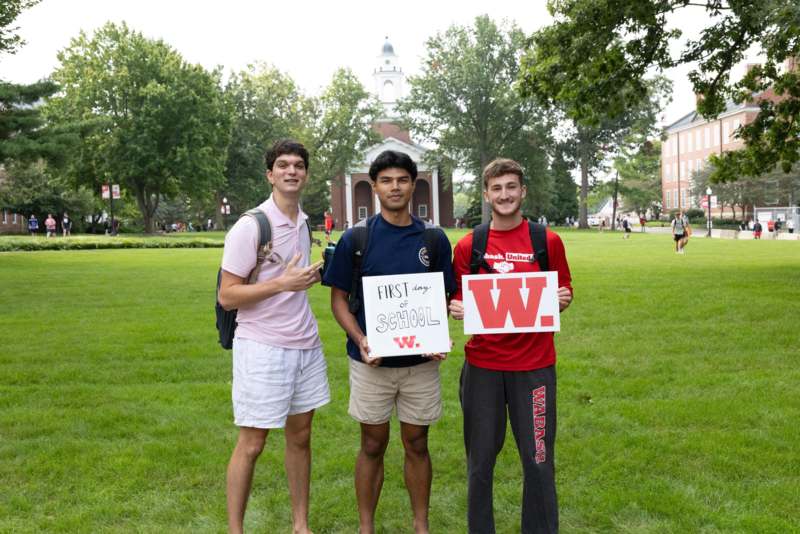a group of men standing in a grassy area holding up a sign