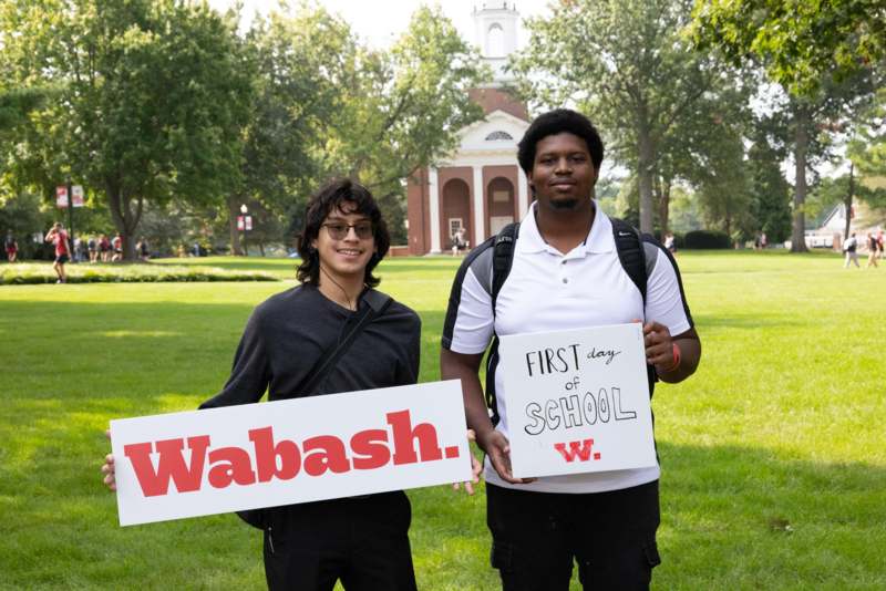 two men holding signs in a park