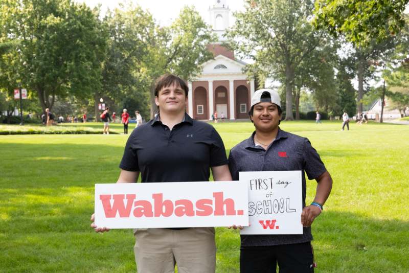 two men holding a sign in front of a building