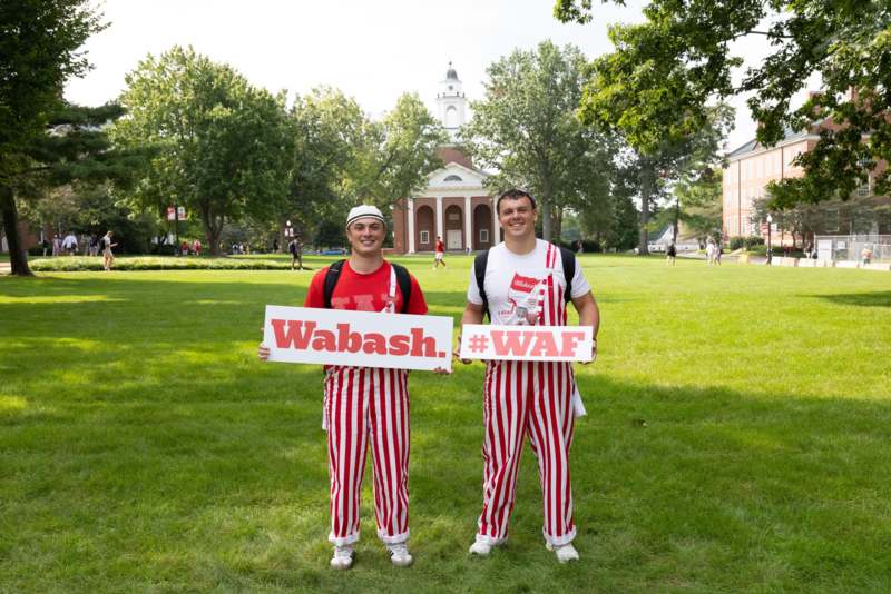two men in striped pants holding signs in front of a building