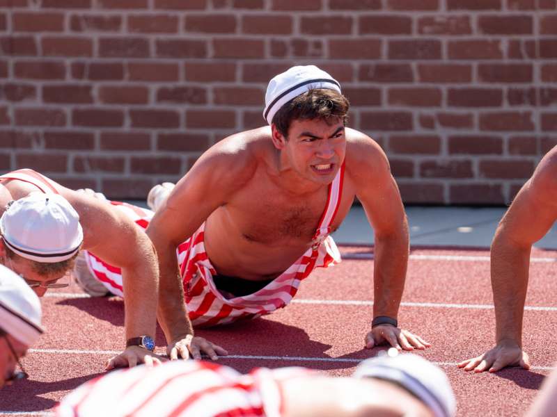 a man in shorts and hat doing push ups on a track