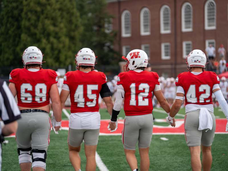 Football vs Wittenberg (09.12.26) - a group of football players holding hands