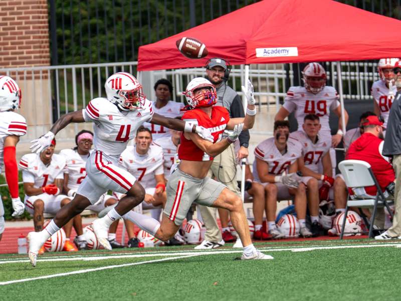 a football player in a red uniform running with a football in the air
