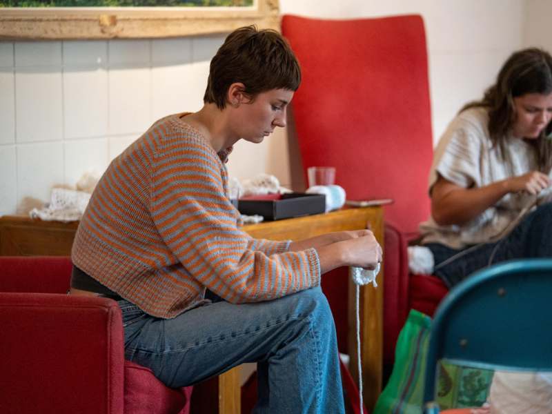 a woman sitting in a chair knitting