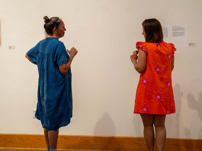 two women standing in front of a white wall