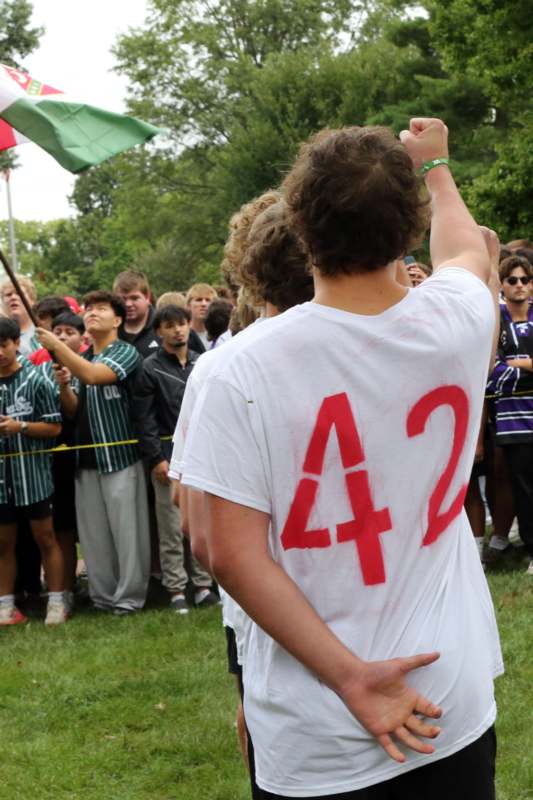 a man in a white shirt with red numbers pointing at a flag