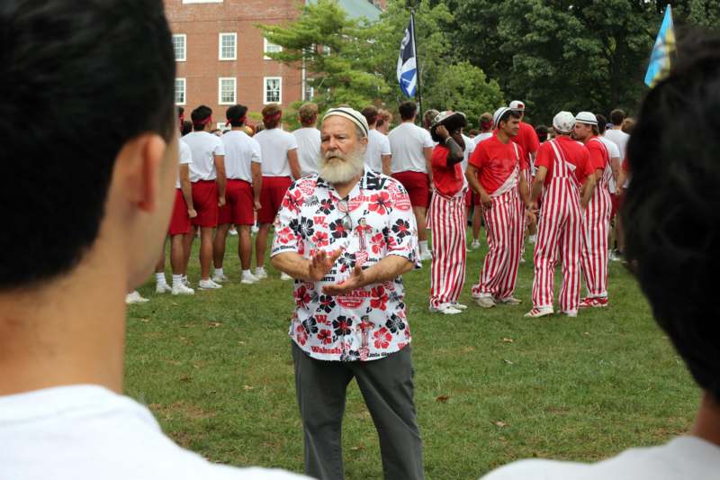 a man in a white shirt and red and white striped pants standing in a line of people