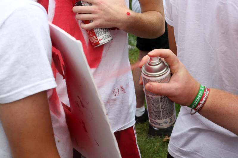 a person spraying red paint onto a person's body