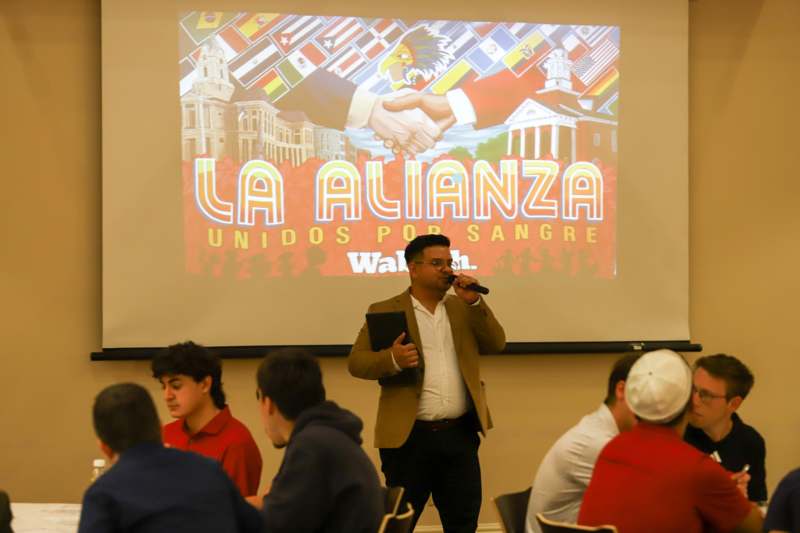 a man speaking into a microphone in front of a large projector screen