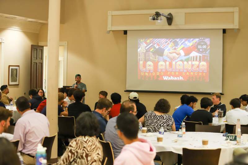 a group of people sitting at tables and a projector screen