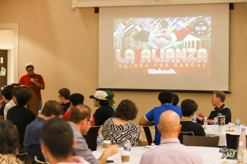 a group of people sitting at tables in front of a projector screen