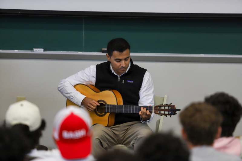 a man playing a guitar in a classroom