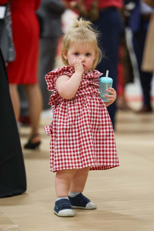 a baby girl holding a bottle and touching her nose