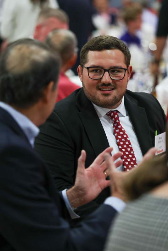 a man in a suit and tie talking to another man