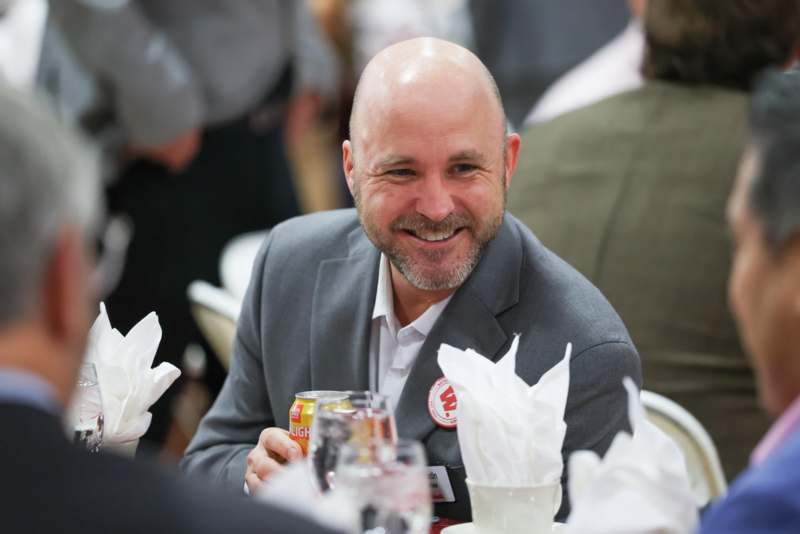a man smiling at a table with a can of beer