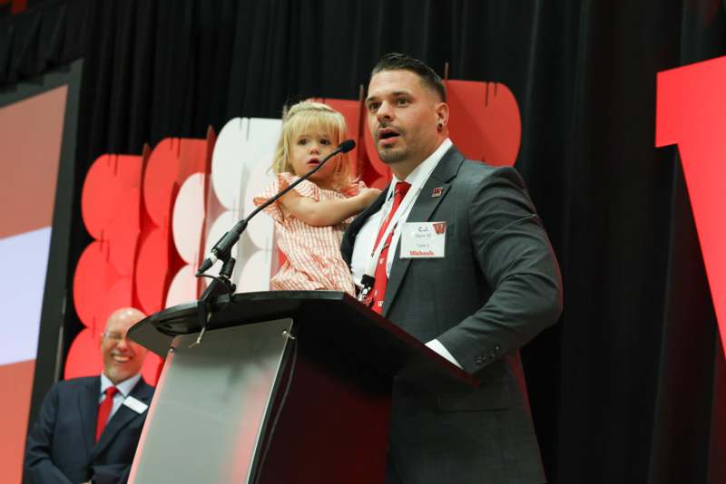 a man standing at a podium with a child on his lap