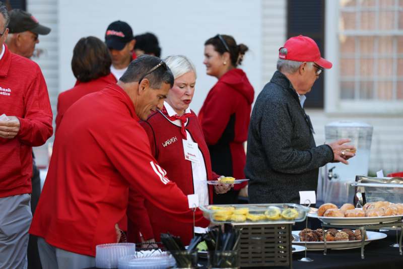 a group of people standing around a table with food