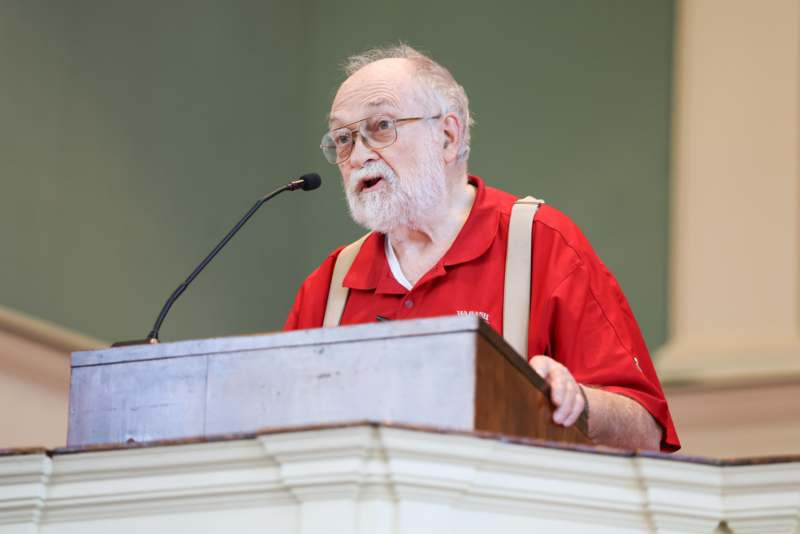 a man in a red shirt speaking into a microphone
