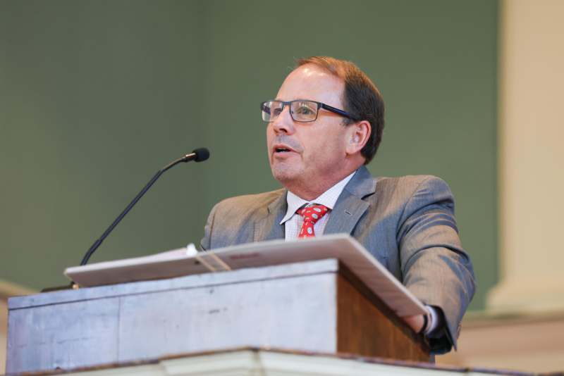 a man in a suit and tie speaking into a microphone