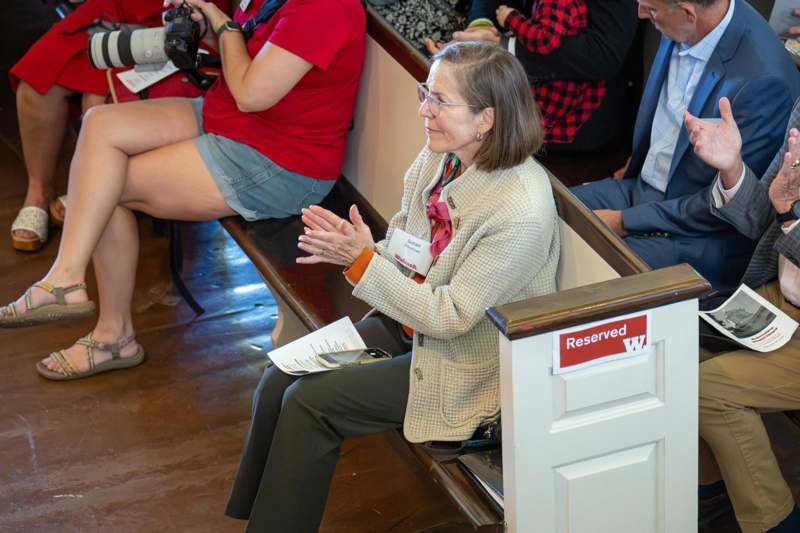 a woman sitting on a bench clapping