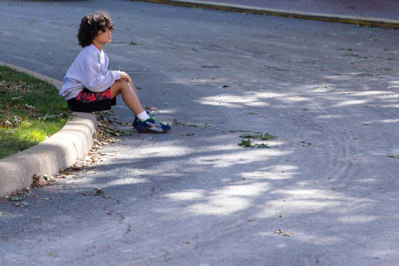 a boy sitting on the side of a road