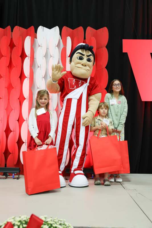 a group of people standing next to a mascot
