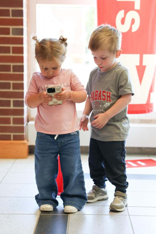 a boy and girl looking at a cellphone