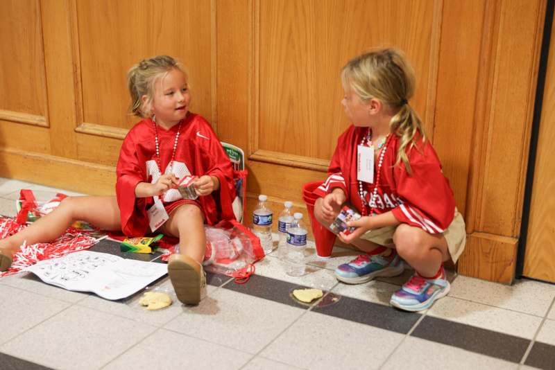 a couple of young girls wearing red shirts sitting on the floor