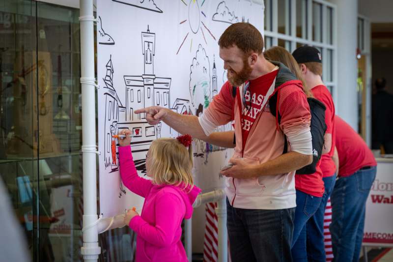 a man and a girl drawing on a white board