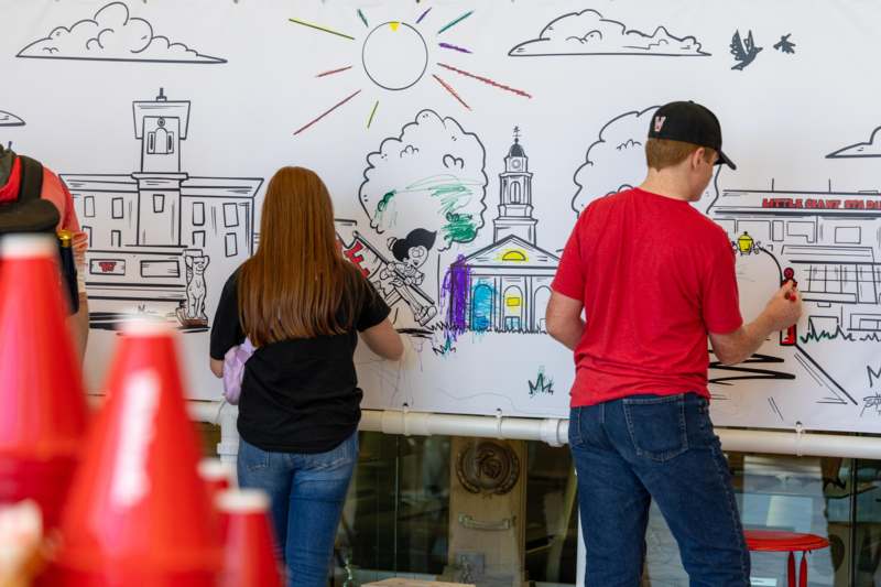 a group of people painting on a large white board